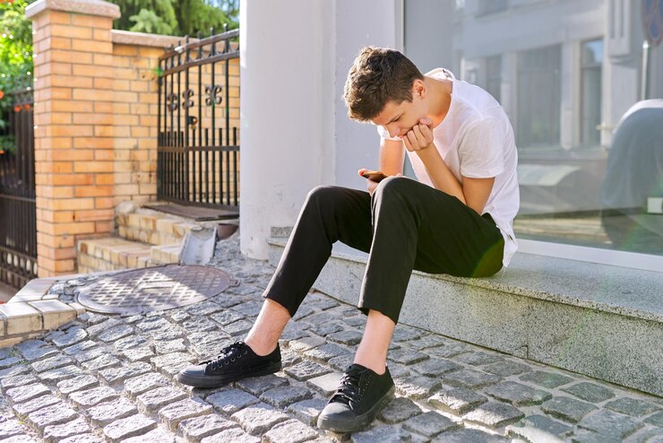 Foto jongen tiener 1617 jaar oud met smartphone zittend op straat van zomer stad man leest een online bericht bladert door sociale netwerken typen tekst