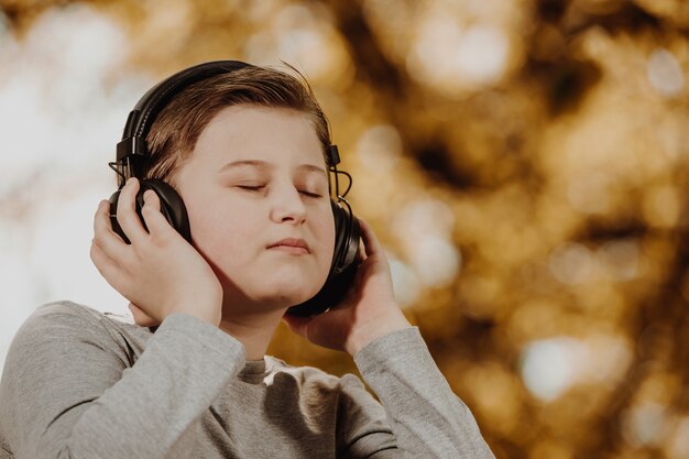 Jongen tiener rustgevende muziek luisteren in een bos tijdens mooie zonnige dag, ontspannen, daad van meditatie