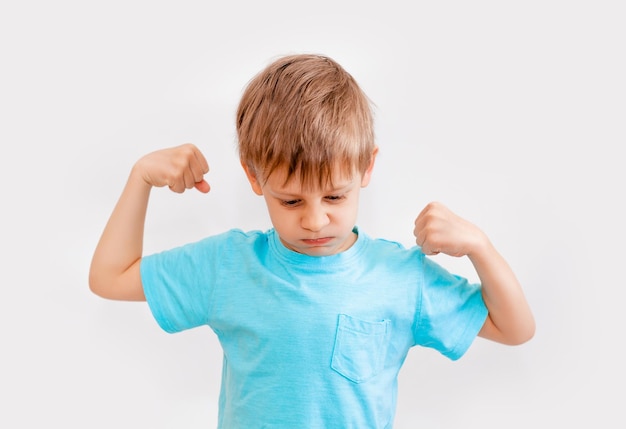 Jongen toont kracht. kleine jongen van vijf laat zijn spieren zien