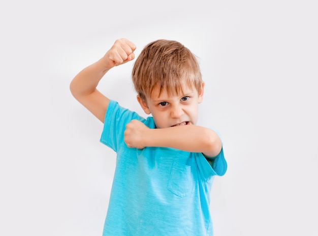 Jongen toont kracht. kleine jongen van vijf laat zijn spieren zien