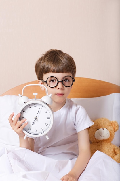 Jongen van 6 jaar in bed met grote wekker