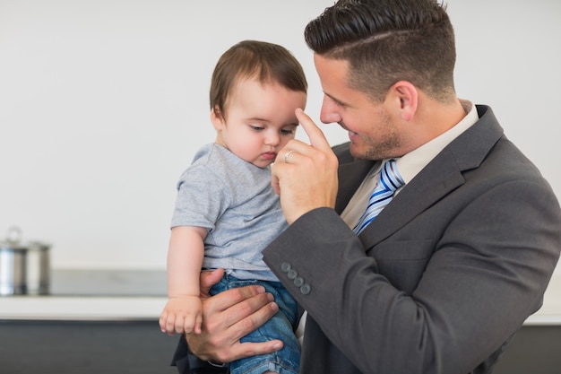 Jongen van de zakenman de dragende baby in keuken