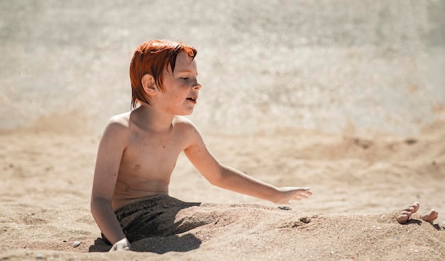 Jongen van negen jaar op het strand graaft in het zand