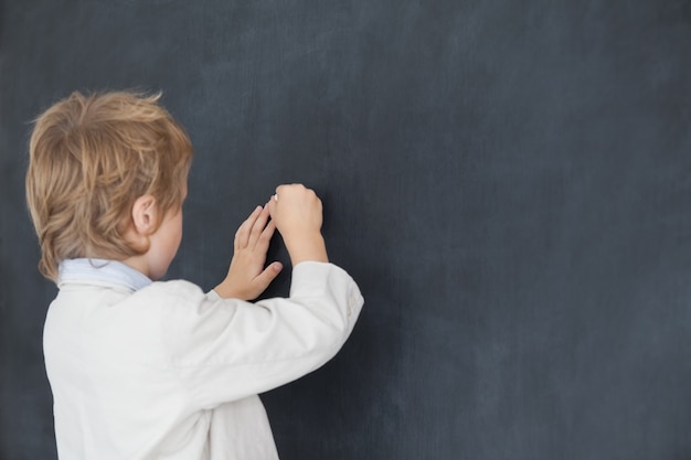 Jongen verkleed als leraar en schrijft op zwarte bord