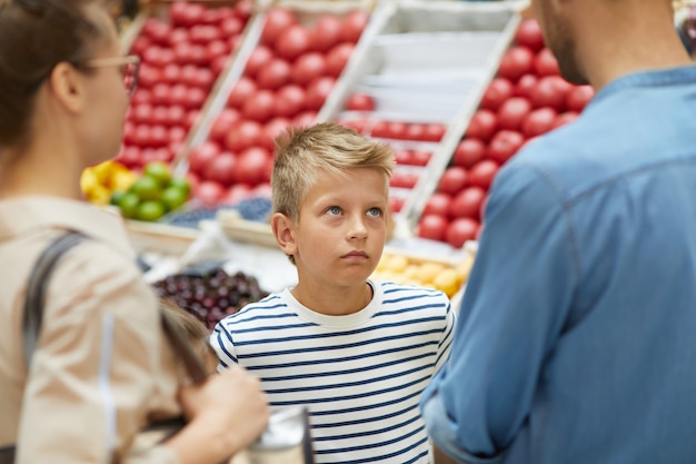Foto jongen winkelen met ouders in de supermarkt