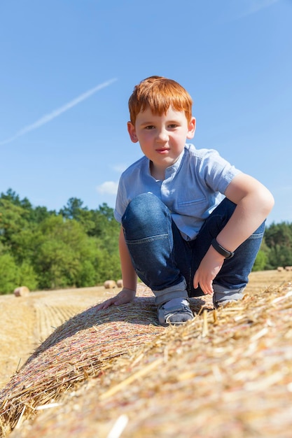 Jongen zit bovenop een stapel gouden stro