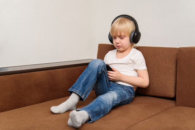 Jongen zit op de bank en kijkt naar smartphone. Problemen van moderne kinderen.