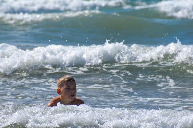 Jongen zwemt in de zee in de golven. het kind rust actief aan zee op vakantie