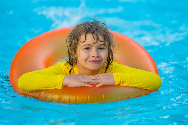 Jongen zwemt in het zwembad met drijver zwemmen zomervakantie kind zwemmen in het zwempil op opblaasbare ring kind met