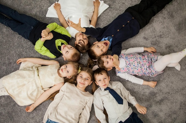 Jongens en meisjes in cirkel. Gelukkige kinderen die plezier hebben. kinderen gaan samen liggen. Gelukkige kinderen liggend op de vloer in een cirkel met handen. Bovenaanzicht. Groep kinderen mooie glimlach die op de vloer ligt