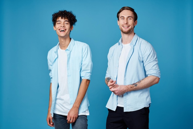 Foto jongens in identieke shirts en een t-shirt op een blauwe achtergrond, vrienden gebaren met hun handen