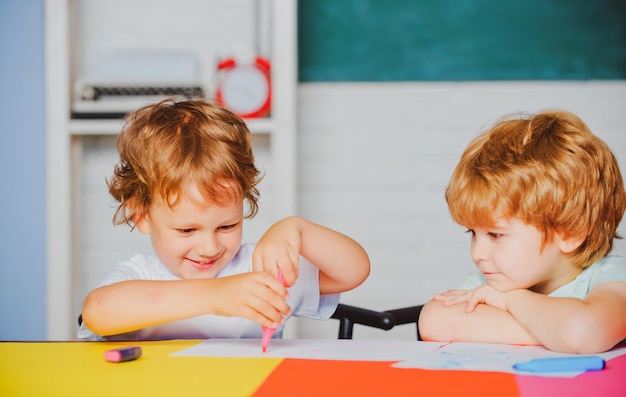 Jongens Leerlingen van de basisschool tekenen op de school Vrolijk lachende kleine leerlingen die plezier hebben Gelukkige leuke slimme jongens leerlingen