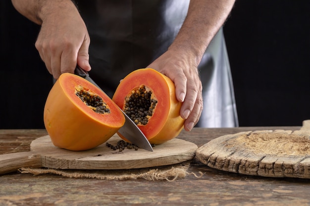 Jongens snijden Ripe papaya op houten achtergrond