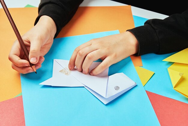 Jongenshanden die origamihond maken met kleurrijke vellen papier, creatief onderwijs voor kinderen