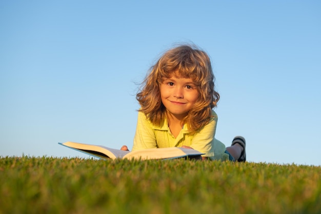 Jongenskind leesboek liggend op groen gras