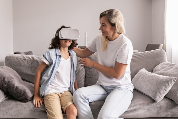 Jongenskind met een virtual reality-headset met zijn moeder vr-bril in de woonkamer thuis met plezier