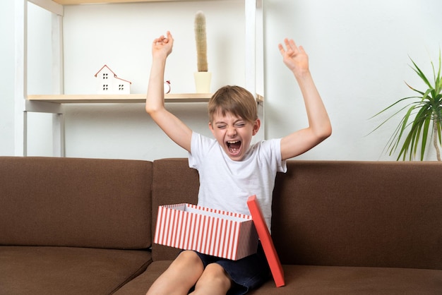 Jongenstiener verheugt zich en heeft plezier met het ontvangen van cadeau Gelukkig kind met cadeau