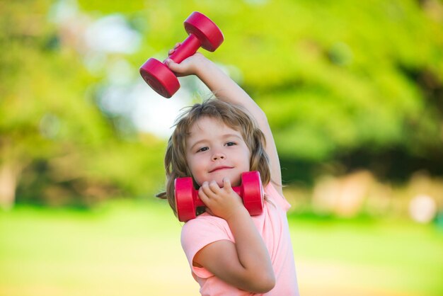 Jongenstraining in park Kindersport Kind oefenen met halters Sportief en fitness kind met halter buiten Kindersport Actieve gezonde levensstijl voor kinderen Gezonde activiteiten levensstijl voor kinderen