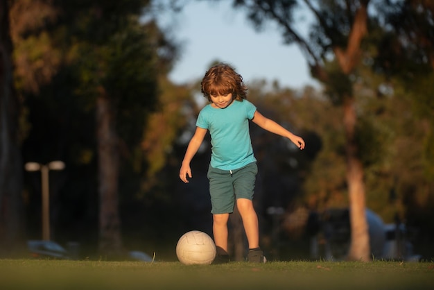 Jongensvoetballer die voetbal schopt op het sportveld Actieve kinderen Kindvoetballer in park