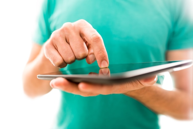 Jongere die een tabletcomputer navigeert en het touchscreen met een vinger activeert terwijl hij op internet surft of gegevens invoert, close-up van de handen.