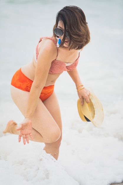 Jongere vrouw die bikinikostuum het spelen met gelukemotie draagt op het strand van de de zomervakantie