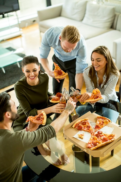 Jongeren die pizza eten en cider in het moderne binnenland drinken