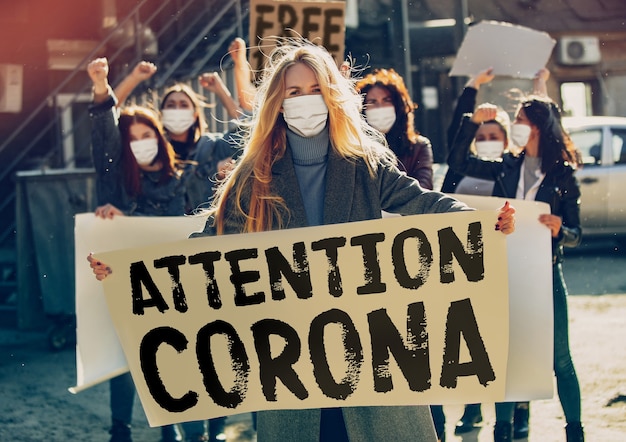 Foto jongeren die protesteren tegen het stoppen van de pandemie van het coronavirus op straat. blanke vrouwen hebben een ontmoeting over een probleem in de geneeskunde, het gezondheidszorgsysteem, de gevarenepidemie. kopieerruimte. stop het coronavirus, covid-19.