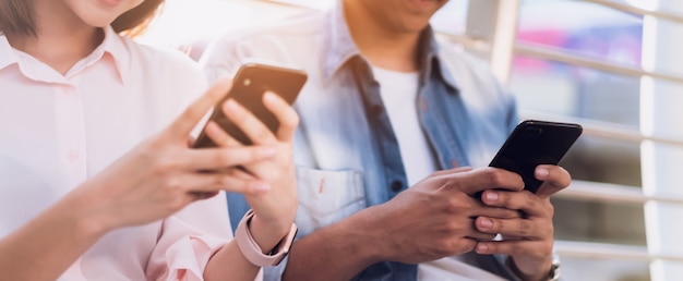 Foto jongeren gebruiken smartphone en glimlachen terwijl ze op vrije tijd zitten.