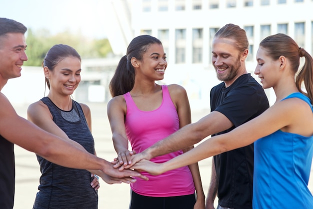 Jongeren in sportkleding hand in hand gestapeld