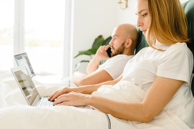 Jongeren thuis of millennial mooi paar in het hotel met behulp van internetverbinding en technologie apparaten zoals computer laptop.