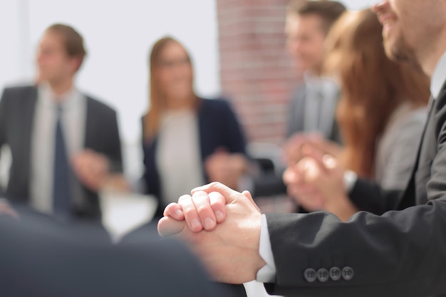 Jongeren zitten in een cirkel, houden elkaars hand vast en glimlachen