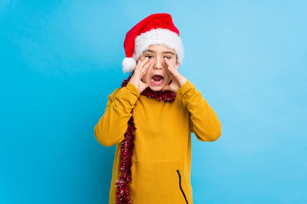 Jongetje vieren kerstdag dragen een kerstmuts geïsoleerd schreeuwen opgewonden aan de voorkant.