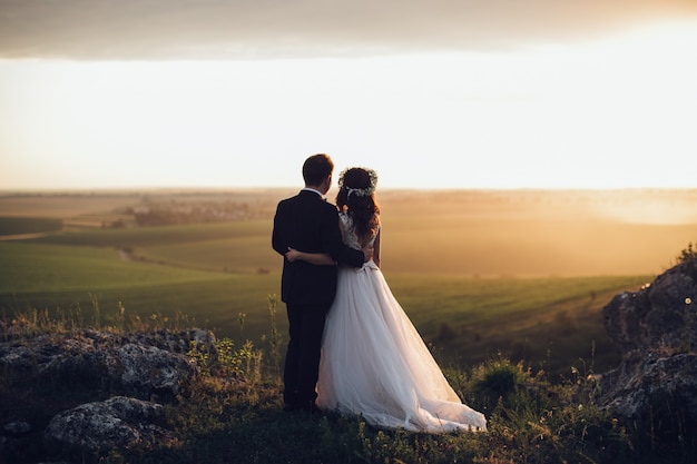 Foto jonggehuwden die zich op landschap stellen