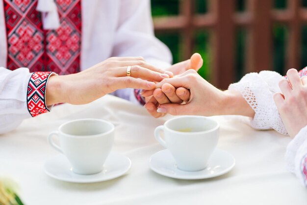 Jonggehuwden hand in hand en trouwring op ringvinger jongen en meisje in café hete koffie drinken