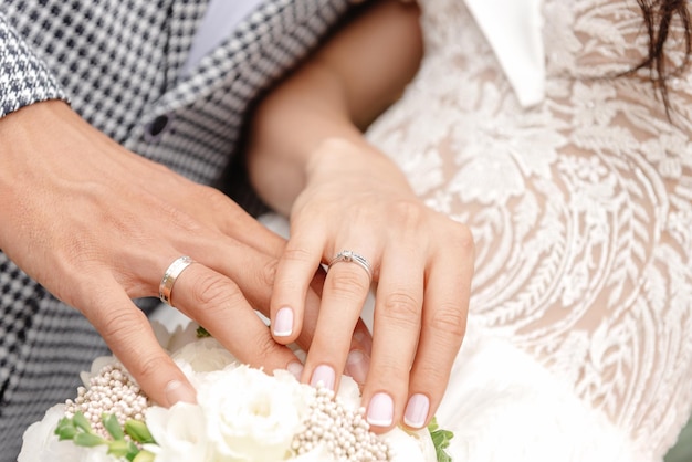 Jonggehuwden hand in hand hand in hand op de voorgrond close-up van jonge koppels handen met trouwring
