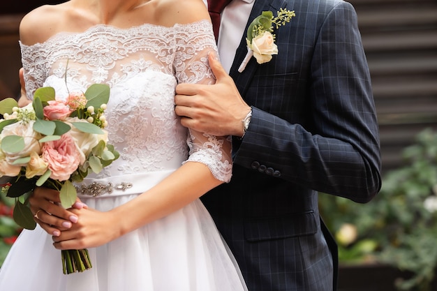 Jonggehuwden op huwelijksdag, bruidspaar met bruiloft boeket bloemen, bruid en bruidegom