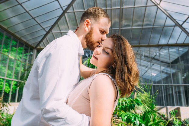 Jonggehuwden staan in een groene botanische tuin een man kust de bruid