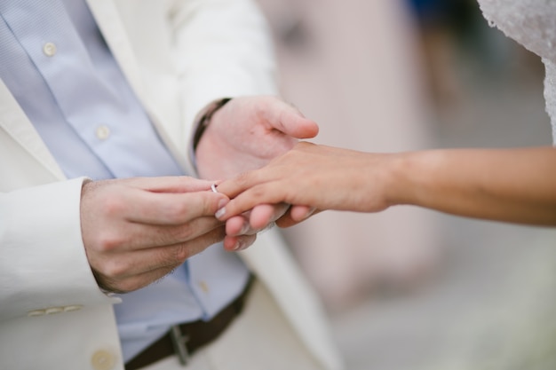 Jonggehuwden wisselen ringen, bruidegom legt de ring op de hand van de bruid