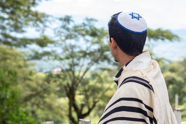Foto joodse man kijkt naar een landschap gekleed in talliet en keppel gezien vanaf de achterkant