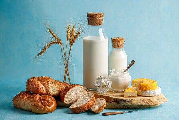 Joodse vakantie Sjavoeot concept met zuivelproducten kaas brood melkfles op lichtblauwe achtergrond