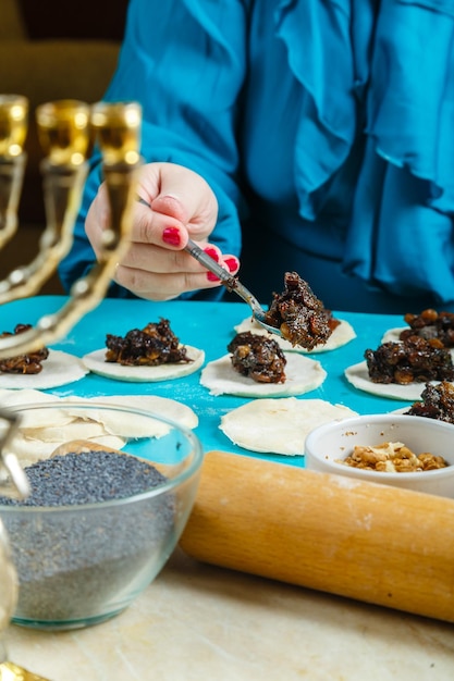 Joodse vrouwen doen maanzaadvulling op het deeg voor gomentashi-koekjes op de Purim-vakantie