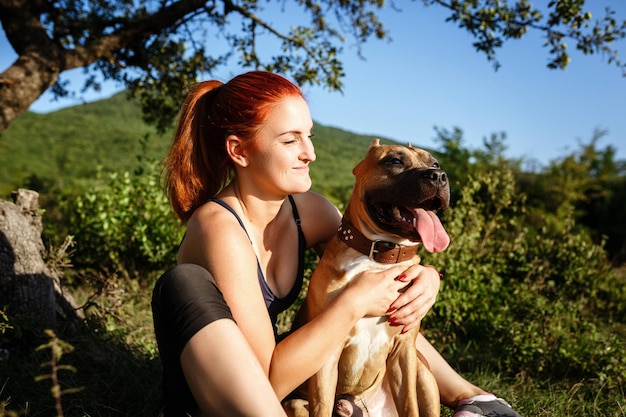 Jouful jong meisje streelt hun hond met sportkleding die geniet van hun tijd en vakantie in het zonnige park