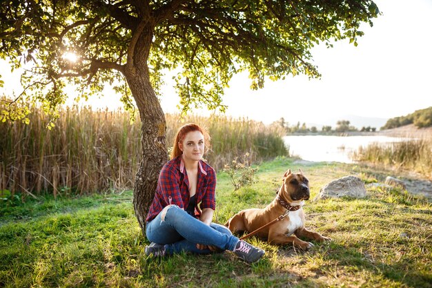 Jouful young girl caressing their dog wearing sport clothing enjoying their time and vacation in sunny park