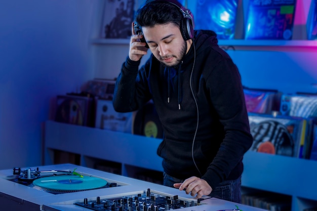 Photo joven dj colocando un disco de vinilo en un tornamesa para mezclar musica en una tienda de discos