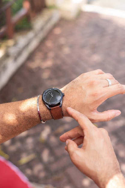 Joven mirando su reloj de muÃ±eca en el parque, toma cerrada