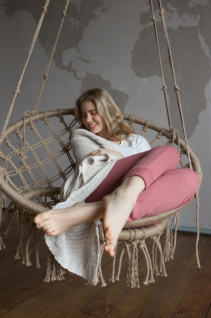 Photo joy concept, beautiful young girl on the swing in cozy room