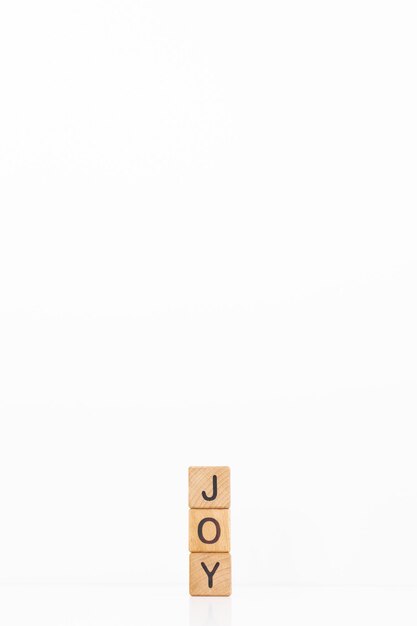 喜びの言葉は、白い背景の上の木製の立方体に書かれています木製の要素のクローズアップ