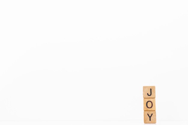 Joy word is written on wooden cubes on a white background Closeup of wooden elements