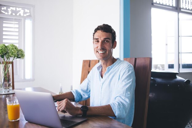 Joyful adult man using laptop at home