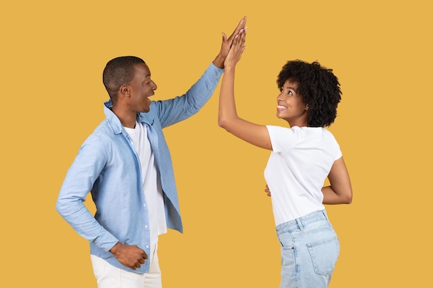 Joyful african american couple highfiving with the man in a light blue shirt